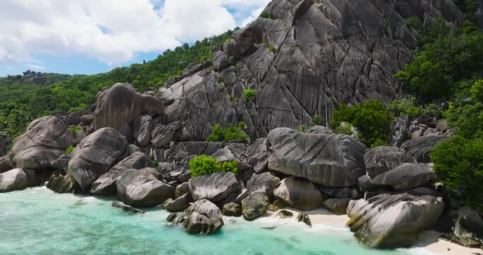 Granite formations along the coastline with turquoise waters and lush tropical vegetation. Seychelles, La Digue.