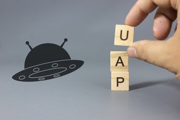 UFO silhouette with the word UAP, representing unidentified aerial phenomena, alien sightings, mysterious flying objects, and modern discussions, theory controvertion, science about unexplained events © bizdof photo