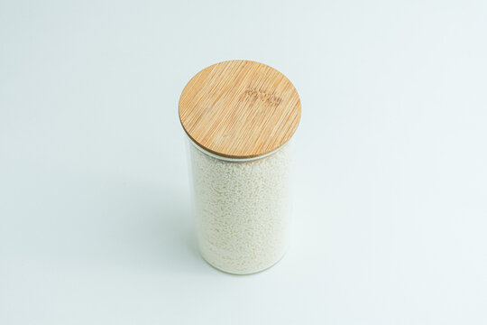 Glass jar with wooden lid filled with mushroom bouillon powder seasoning isolated on white background