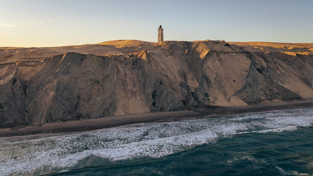 Aerial view of Rubjerg Knude lighthouse perched on the dramatic sandy cliffs overlooking the North Sea in Lokken, Denmark.