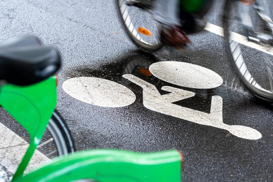 Bicycles crossing a wet bike lane in Lyon with bicycle symbol and motion blur emphasizing urban cycling infrastructure and movement through the city