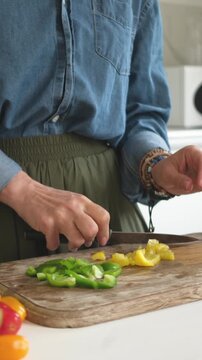 Woman Slicing Yellow And Green Pepper For Salad. Vertical Video