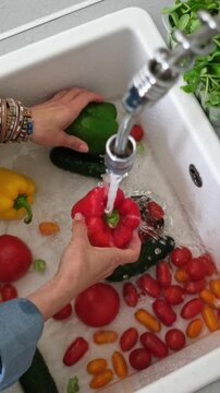 View From Above Of A Woman Washing Tomatoes And Peppers Over A Sink. Vertical video