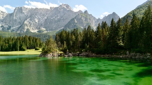 Aerial view of Laghi di Fusine alpine lake surrounded by conifer forest with the Julian Alps behind, near Tarvisio, Friuli-Venezia Giulia, Italy
