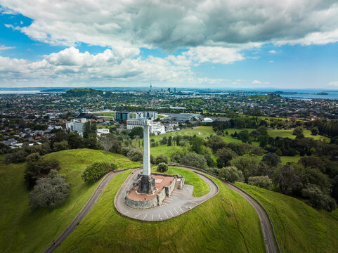 Auckland, Auckland Region, New Zealand - 26 November 2021: View of One Tree Hill monument on a grassy volcanic cone with the city skyline in the background.