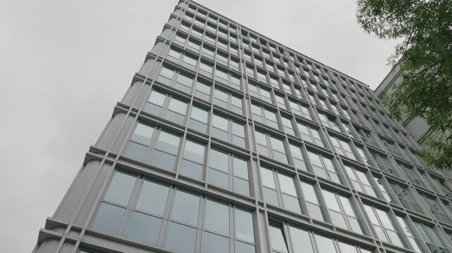 Glass skyscraper facade rises steeply into overcast sky