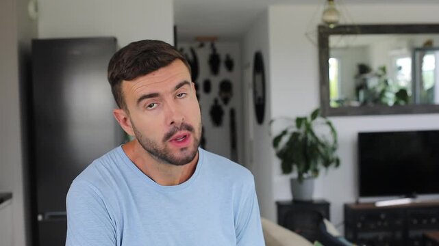 Man whistling and gently dancing to an easy rhythm in front of the camera before smiling.