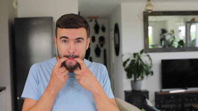 Man putting two fingers in his mouth to blow a loud whistle toward the camera before smiling
