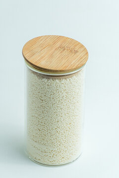 Glass jar with wooden lid filled with mushroom bouillon powder seasoning isolated on white background