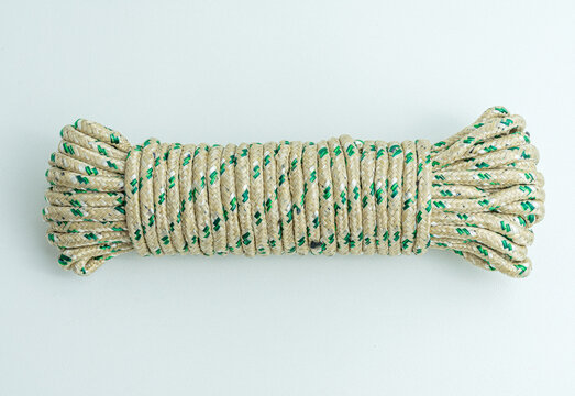Rolled bundle of green and white twisted string rope isolated on white background