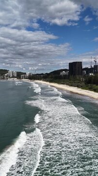 Aerial drone view of surf rolling onto Burleigh Heads beach, Gold Coast, Queensland Australia - vertical video