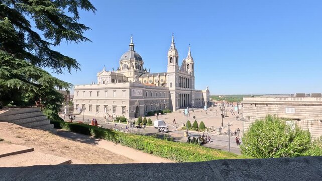 Madrid, Spain, 08-05-2026. Tracking shot showcasing the grand facade and dome of the Almudena Cathedral under a sunny blue sky, in the old town of Madrid city, in Spain (Europe)