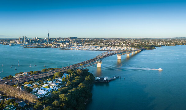 Auckland, New Zealand - 09 June 2023: View of the Auckland Harbour Bridge spanning the Waitemata Harbour with the city skyline and marina in the background.