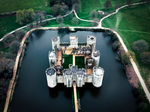 Robertsbridge, United Kingdom - 19 April 2023: View of Bodiam Castle surrounded by a moat with green lawns and trees.