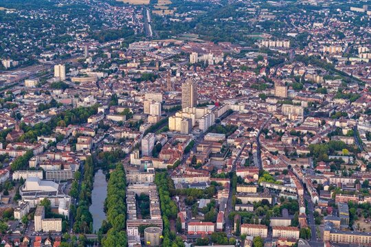 Aerial view of the urban landscape of Mulhouse featuring dense residential blocks, a prominent high-rise building, and green spaces in Mulhouse, Grand Est, France.