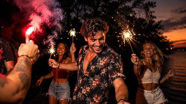 Young Adults Enjoying a Vibrant Outdoor Night Party with Sparklers Dancing and Celebrating Together.