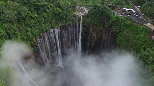 Water cascading down the tumpak sewu waterfall in east java surrounded by tropical rainforest