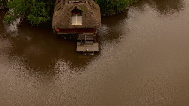 Aerial view of a person on a stilt house in a remote indigenous village in the amazon rainforest