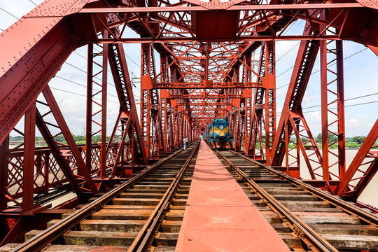 Pabna, Bangladesh - 17 August 2025: View of the iconic red steel truss Hardinge Bridge over the Padma River with a train crossing the tracks.