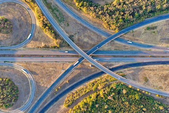 Aerial view of the highway interchange featuring intersecting roads, surrounding green forests, and sparse traffic in Sausheim, Grand Est, France.