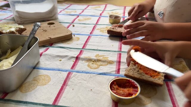 Table-level detail shot showing the hands of two children independently preparing their own snack.