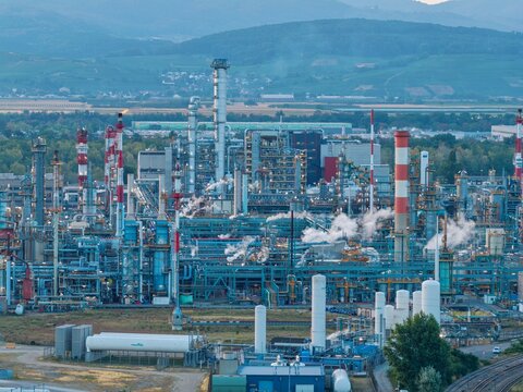 Aerial view of the industrial refinery complex with tall chimneys, intricate piping systems, and steam emissions in Bantzenheim, Grand Est, France.