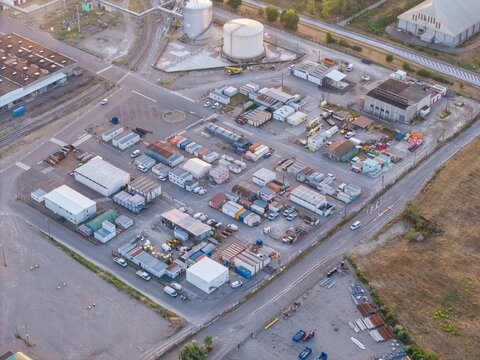 Aerial view of an industrial logistics site featuring numerous shipping containers, temporary office structures, storage tanks, and parked vehicles in Bantzenheim, Grand Est, France.