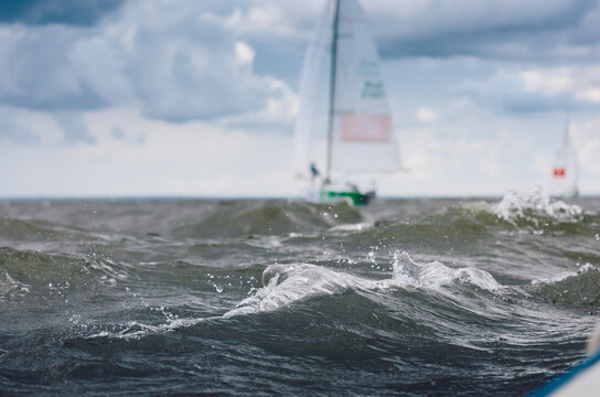 magic splashing water, Russia, St.Petersburg, Yachtsmen are sitting amicably on board of the sailing boat in sailing regatta in the Gulf of Finland at sunny day, teamwork