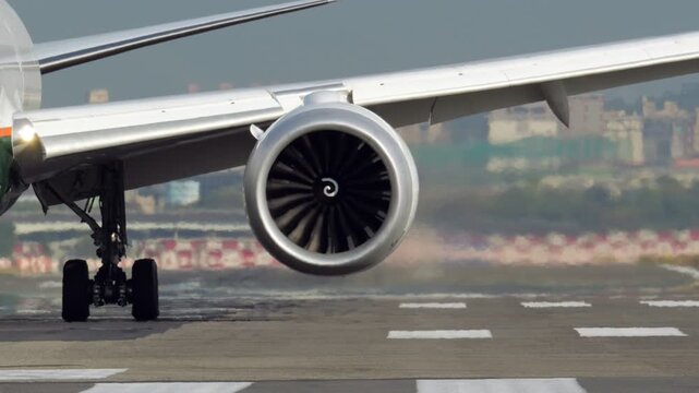 Impressive and captivating close-up front view of commercial airliner taxiing slowly on runway after landing. massive jet engine turbine spins in slow motion at idle