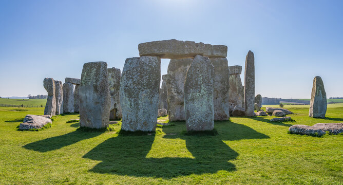 United Kingdom - 20 April 2023: View of Stonehenge, a prehistoric monument with massive standing stones set in a grassy landscape under a clear blue sky.