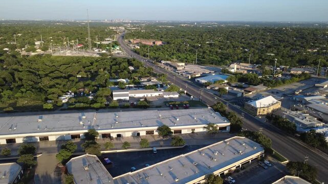 Elongated warehouse roofs, roadway corridors extend along Evers Road across Northwest Bexar County. Commercial logistics hubs parallel suburban tree lines across San Antonio, Texas