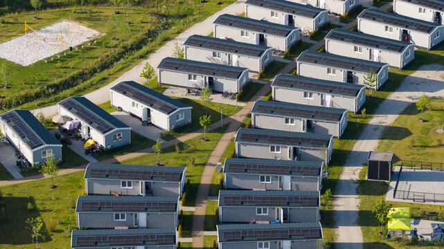Aerial view of modern modular holiday homes with solar panels arranged in rows within a green park setting in Venlo, Limburg, Netherlands.