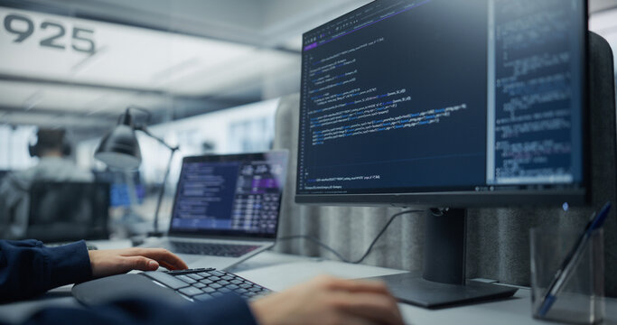 Unrecognizable Software Developer Typing Program Code and Sql Database Queries on a Desktop Computer Display and Laptop, Building a Cloud Application in an Office With a Diverse Team of Programmers.