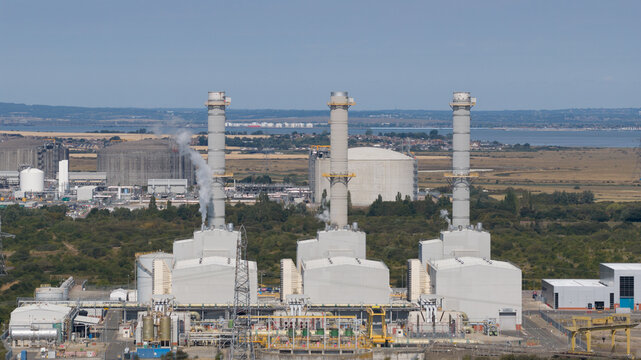 Aerial view of Damhead Creek Power Station with its three tall chimneys and industrial facilities set against the landscape in Rochester, England, United Kingdom.