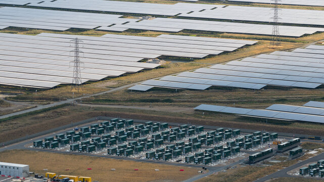 Aerial view of a large solar farm with rows of photovoltaic panels and a grid-scale battery energy storage system in Faversham, England, United Kingdom.