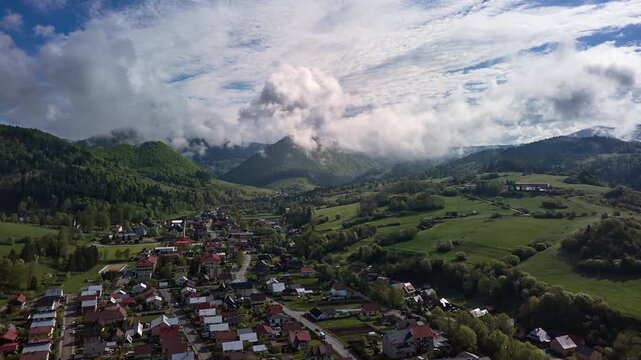 Aerial Hyperlapse of Mountain Village and Clouds Passing Over Green Hills