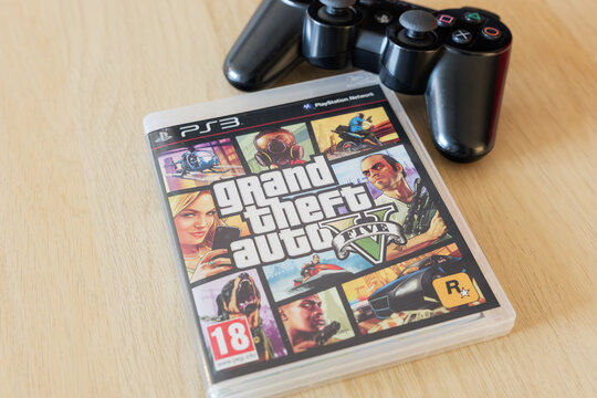 DRESDEN, GERMANY - 19. August 2026: GTA V game with a Playstation controller. Grand Theft Auto 5 from Rockstar Games lying on a table. Close-up of the videogame cover in the case.