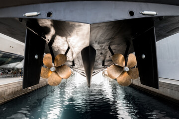 Superyacht being lowered into the water after winter haul out at shipyard, with freshly auti-fauled hull and polished propellers about to touch the water  © lupiphoto