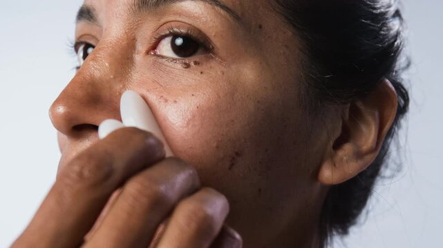 Tilt up close up shot of young Hispanic woman massaging face with gua sha stone. Clip is ideal for skincare brands, beauty tutorials, wellness marketing campaigns