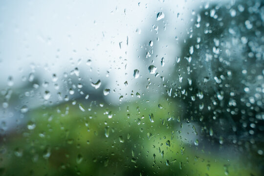 View of raindrops on a window pane with a blurred green background in Riga, Latvia.