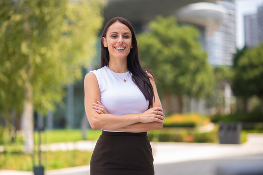 Confident businesswoman smiling with arms crossed in urban park