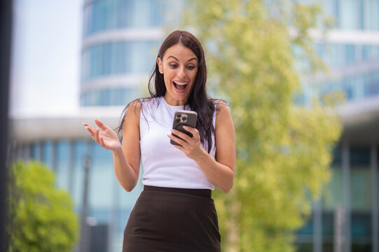 Woman reacting with surprise and happiness to phone message