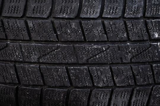 View of a close-up of a black rubber car tire tread with deep grooves and sipes for winter traction in Riga, Latvia.