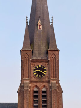 View of the historic brick church tower with a prominent clock face and tall spire in Zaandam, North Holland, Netherlands.