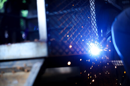 Welding spark metalwork fabrication industrial workshop blue light protective screen bright spark molten metal safety barrier dark workspace