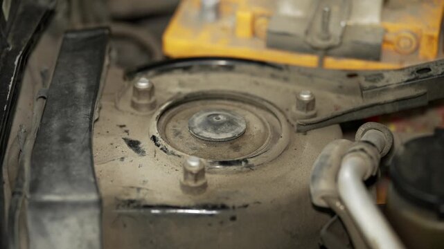A close up of a dusty front shock absorber strut mount.