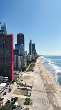 Surfers Paradise coastline from above, surf breaking beside the high-rise strip, Gold Coast, Queensland Australia - vertical video