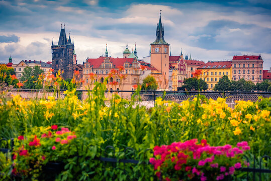 Exciting summer cityscape Prague with Old Town Bridge Tower and Water Tower on the shore of Vltava river. Wonderful morning scene of  Czech Republic - Prague with blooming flowers on foreground. 