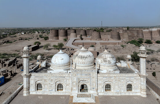 Aerial view of the white marble Derawar Mosque situated in front of the massive ancient walls of Derawar Fort in the desert landscape of Derawar, Punjab, Pakistan.