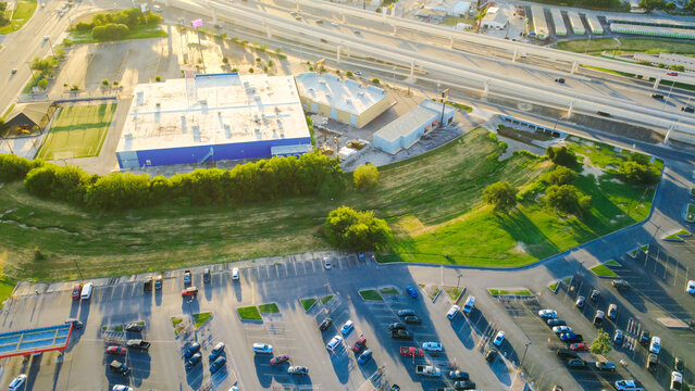 Blue retail buildings, grassy drainage swales border Loop 410 along Evers Road across Bexar County region. Expansive parking lots flank multi tier highway viaducts in San Antonio, Texas